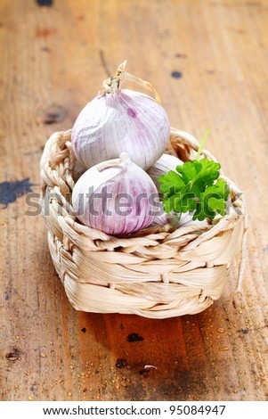 Garlic in a box with parsley on a rustic wooden board