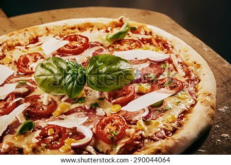 Close Up of Fresh Baked Pizza Topped with Tomatoes, Basil and Cheeses Served on Wooden Pizza Paddle