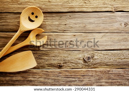 Wooden cooking utensils border on a background of aged weathered vintage wood with a rough rustic texture and plenty of copyspace