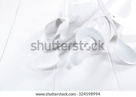 Pure white winter cooking concept with a white rolling pin, spoons and wooden scoop arranged in the corner on a rustic white wooden table with copyspace, low angle view