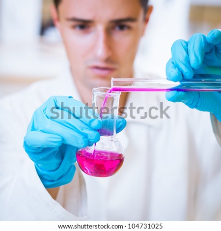 close-up portrait of a young male researcher carrying out experiments in a chemistry research lab (color toned image)