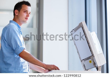 Handsome  young man using a copy machine (shallow DOF; color toned image)