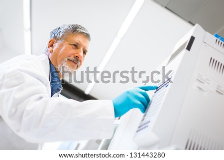 Senior male researcher carrying out scientific research in a lab using a gas chromatograph (shallow DOF; color toned image)