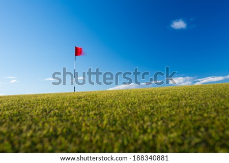 Red golf flag on a golf course, moving in the wind (motion blurred image); St. Andrews, Scotland