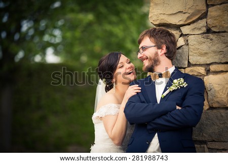 Portrait of a young wedding couple on their wedding day, looking happy, laughing together instead of posing properly for the photographer
