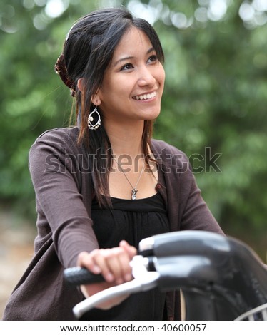Very pretty young asian woman on bike smiling while commuting/biking to work