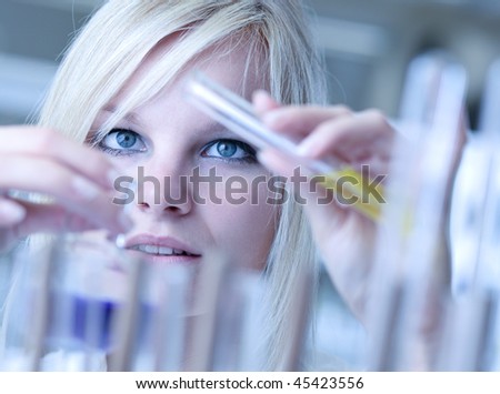 Closeup of a female researcher holding a test tube and a retort and carrying out experiments in a laboratory