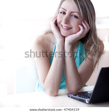 pretty young blonde woman working on a laptop computer, smiling