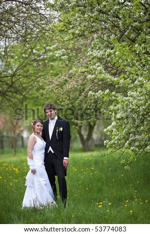 young wedding couple - freshly wed groom and bride posing outdoors on a lovely spring day