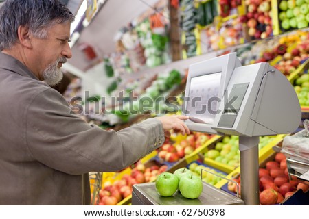Handsome senior man shopping for fresh fruit in a supermarket (shallow DOF, sharp focus on the apples; color toned image)