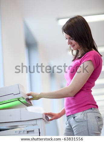 pretty young woman using a copy machine (shallow DOF; color toned image)