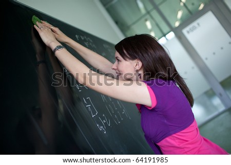 pretty young college student or teacher writing on the chalkboard/blackboard during a math class (shallow DOF; color toned image)
