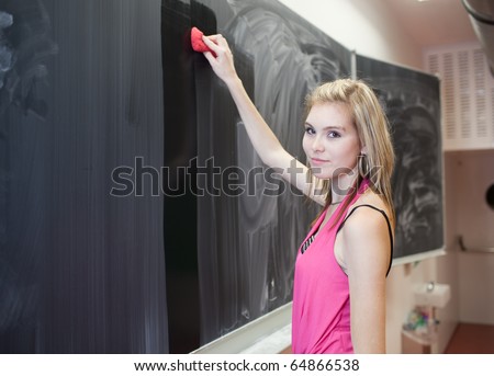 pretty young college student erasing the chalkboard/blackboard during a math class (color toned image)