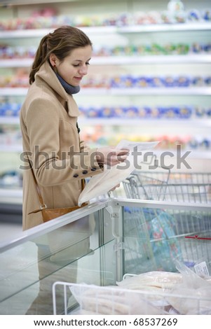pretty young woman buying groceries in a supermarket/mall/grocery store (color toned image; shallow DOF)