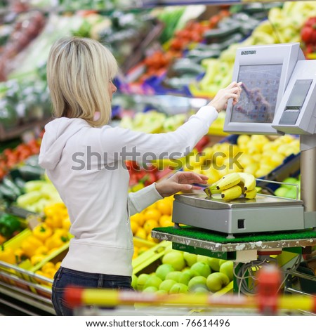 Beautiful young woman shopping for fruits and vegetables in produce department of a grocery store/supermarket