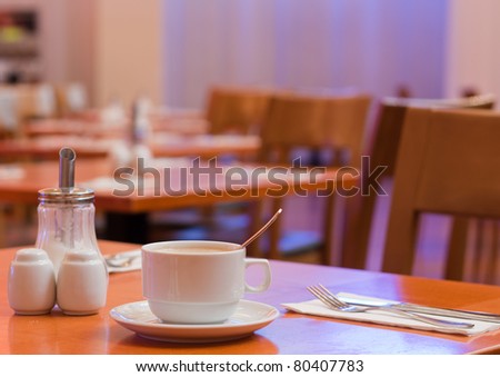 Close up of a cup of coffee on a table set for breakfast in a hotel cafe/restaurant/dining hall