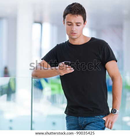 Handsome, young man using his mobile phone in a public area (shallow DOF; color toned image)