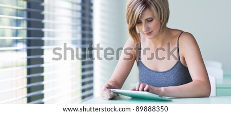 Pretty, young businesswoman/college student using her tablet computer (shallow DOF; color toned image)