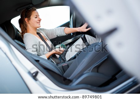 Young female driver playing music in the car (changing CDs)