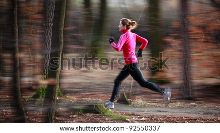Young woman running outdoors in a city park on a cold fall/winter day (motion blurred image)