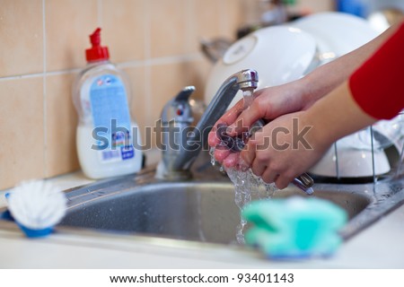 Washing of the dishes - woman hands rinsing dishes under running water in the sink