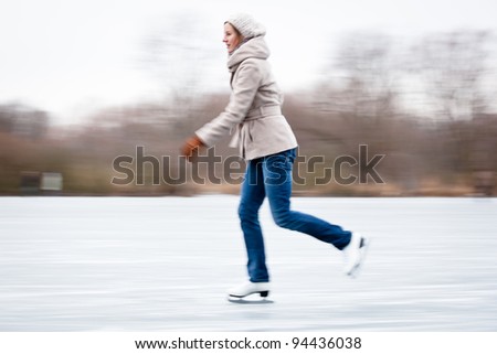 Young woman ice skating outdoors on a pond on a freezing winter day (motion blurred image)