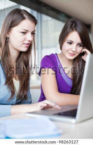 Two female college students working on a laptop computer during class (color toned image)