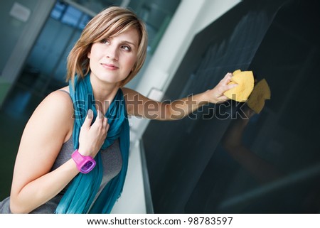 pretty college student/young teacher erasing the chalkboard/blackboard during a math class (color toned image; shallow DOF)