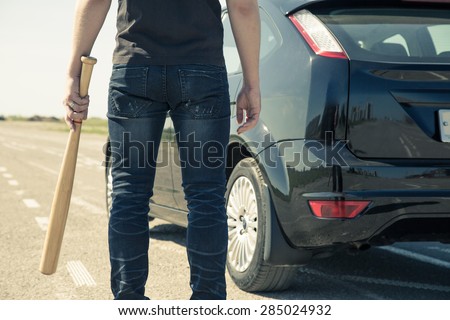 Man with baseball bat in the car on the road