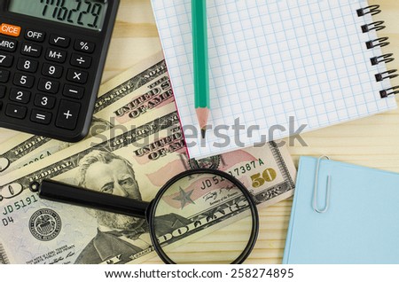Office, business tools with dollars and blank notebook on wooden table