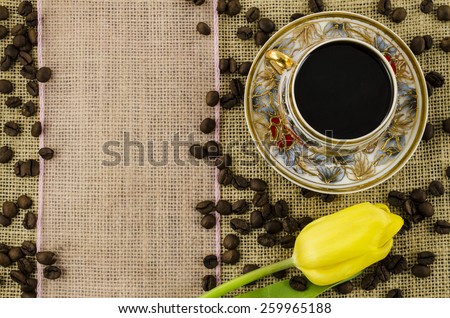 Porcelain coffee cup with yellow flower and pink ribbon on linen background