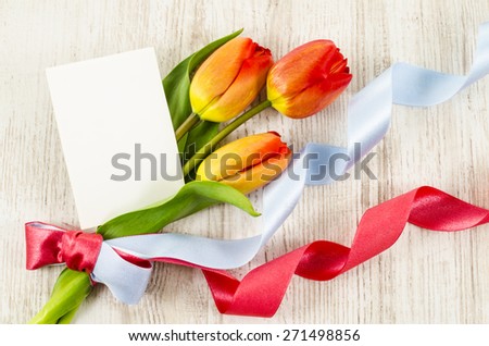 Empty postcard with colorful flowers and ribbon on wooden background