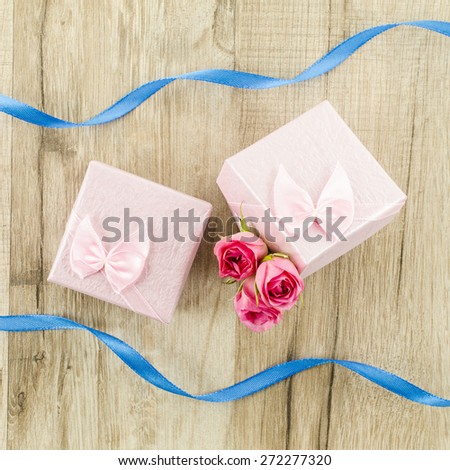 Gift box with rose flower and ribbon on wooden background
