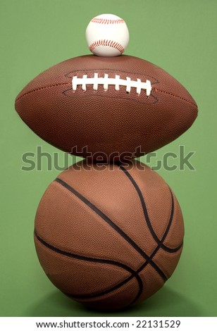 A basketball, football and baseball balance on top of each other