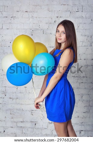 Beautiful teen girl in blue dress with long hair holding colorful air  balloons