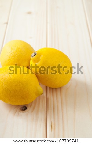 Three yellow lemons on clear wood table