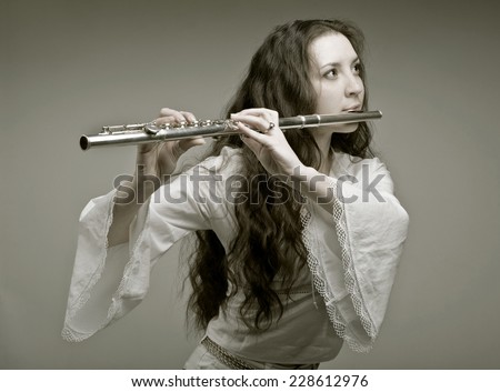 girl plays the flute on a grey background.sepia