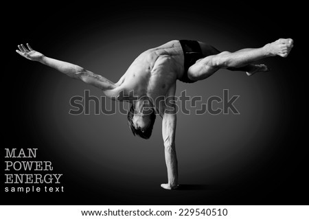 Athlete.Power.Energy.Gym.Men\'s sports figure.Circus actor standing on the hand on a black background.Black-and-white image