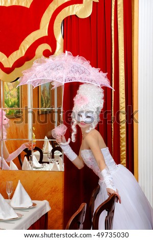 lady in masquerade dress.glamorous lady with an umbrella in the interior of a cafe