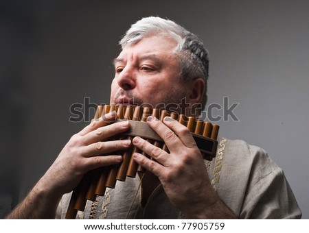musician plays the flute  on a  grey background.musical wind instrument Nye.folk music.ancient musical instrument