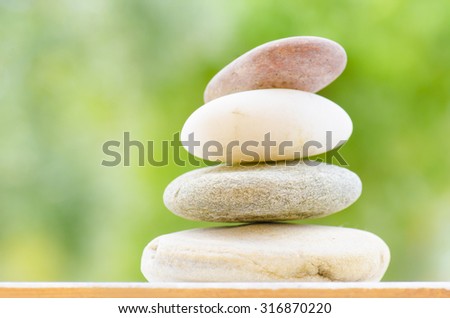 3 rocks pyramid of different colors on wood green background