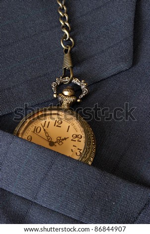 A business mans suit while checking the time on his pocket watch.