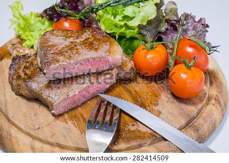 Beef rib eye steak with knife and fork for meat on cutting board