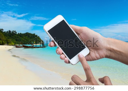 Woman holding smart phone or mobile phone with blank mobile.over blurred beautiful blue and clear sky on beach background for working online on vacation.