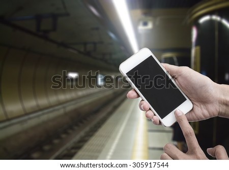 Woman holding smart phone or mobile phone with blank mobile.over blurredSubway tunnel background for working online on vacation.