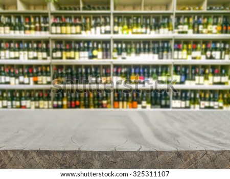Empty wood table top (or shelf) shelf with wine liquor bottle in supermarket blurred background - can montage or display your products