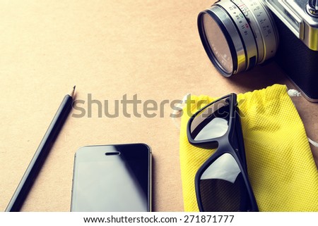 vintage still life details, pencil, sunglasses, camera ,smart phone on wood desk