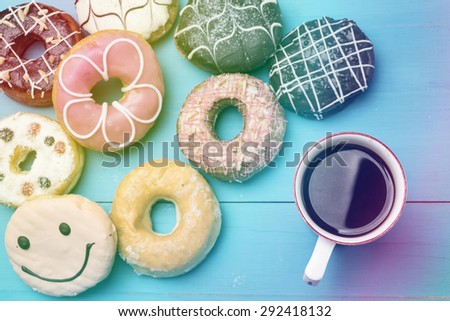Mug of coffee and donuts on wooden desk vintage