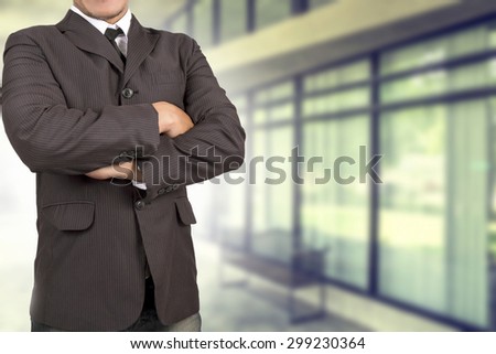 Business man with crossed arms against on office background
