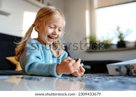 Similar – Image, Stock Photo 4 year old blonde girl with a brightly colored striped sweater sits at a wooden table and draws with a purple pencil on a piece of white paper